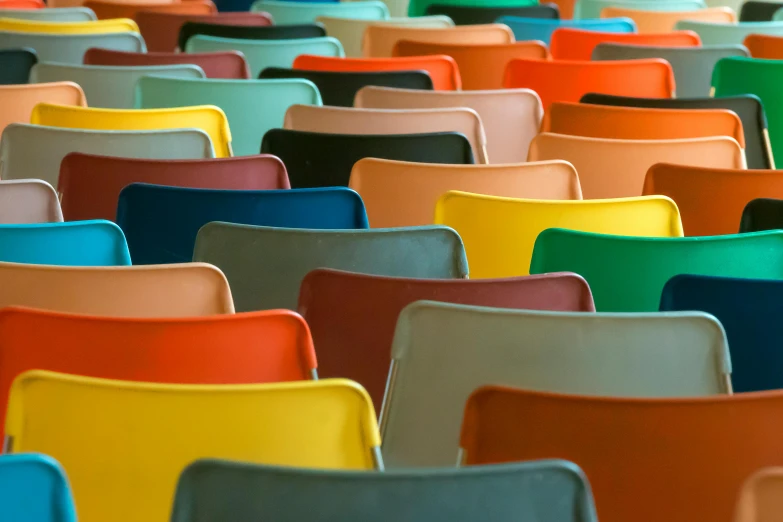 many colorful plastic chairs are stacked on each other