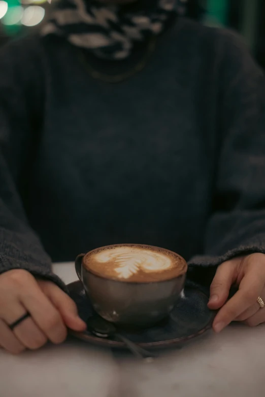 a woman with a black shirt holds a cup with latte art