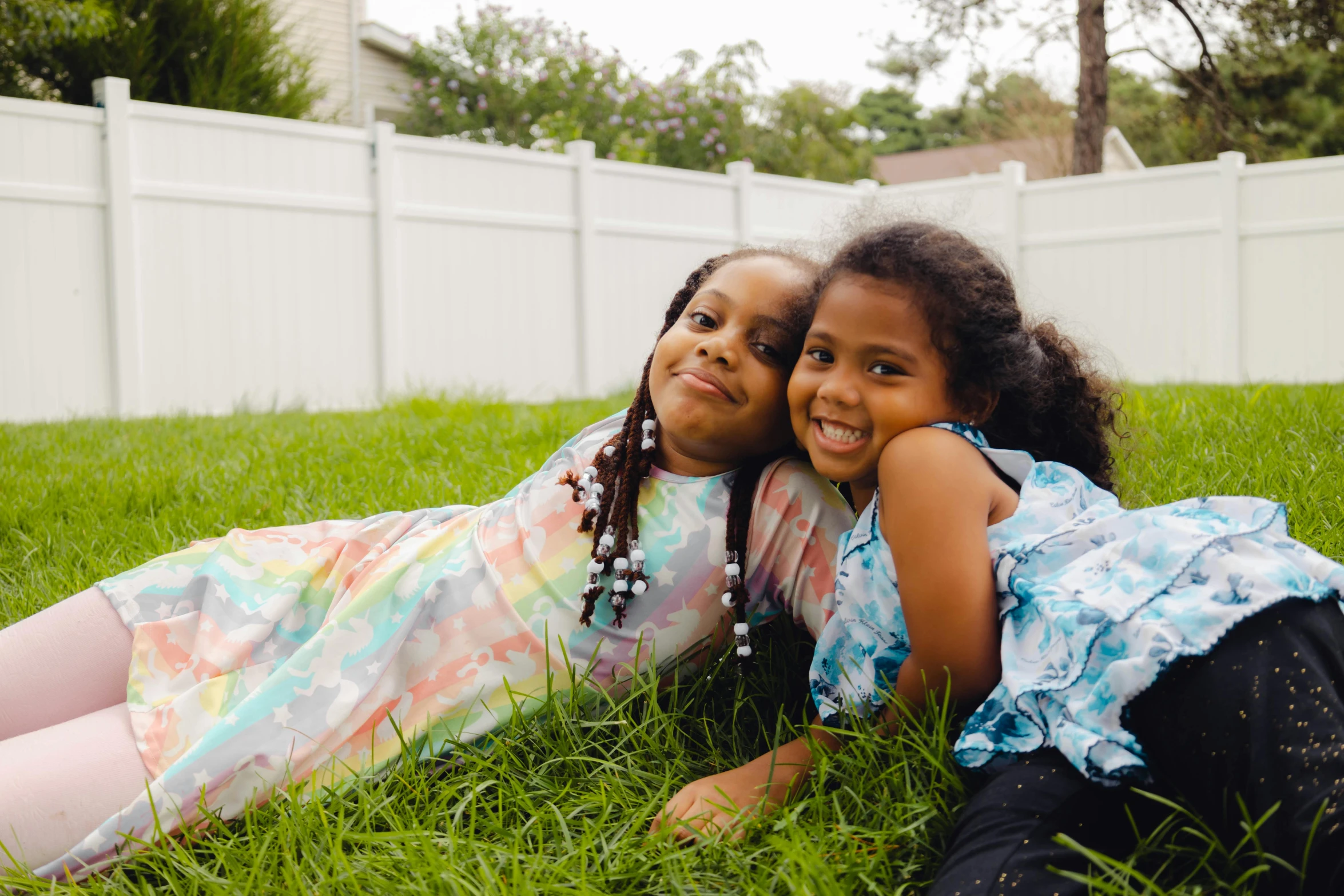 two children, one sitting down and the other laying on grass, playing