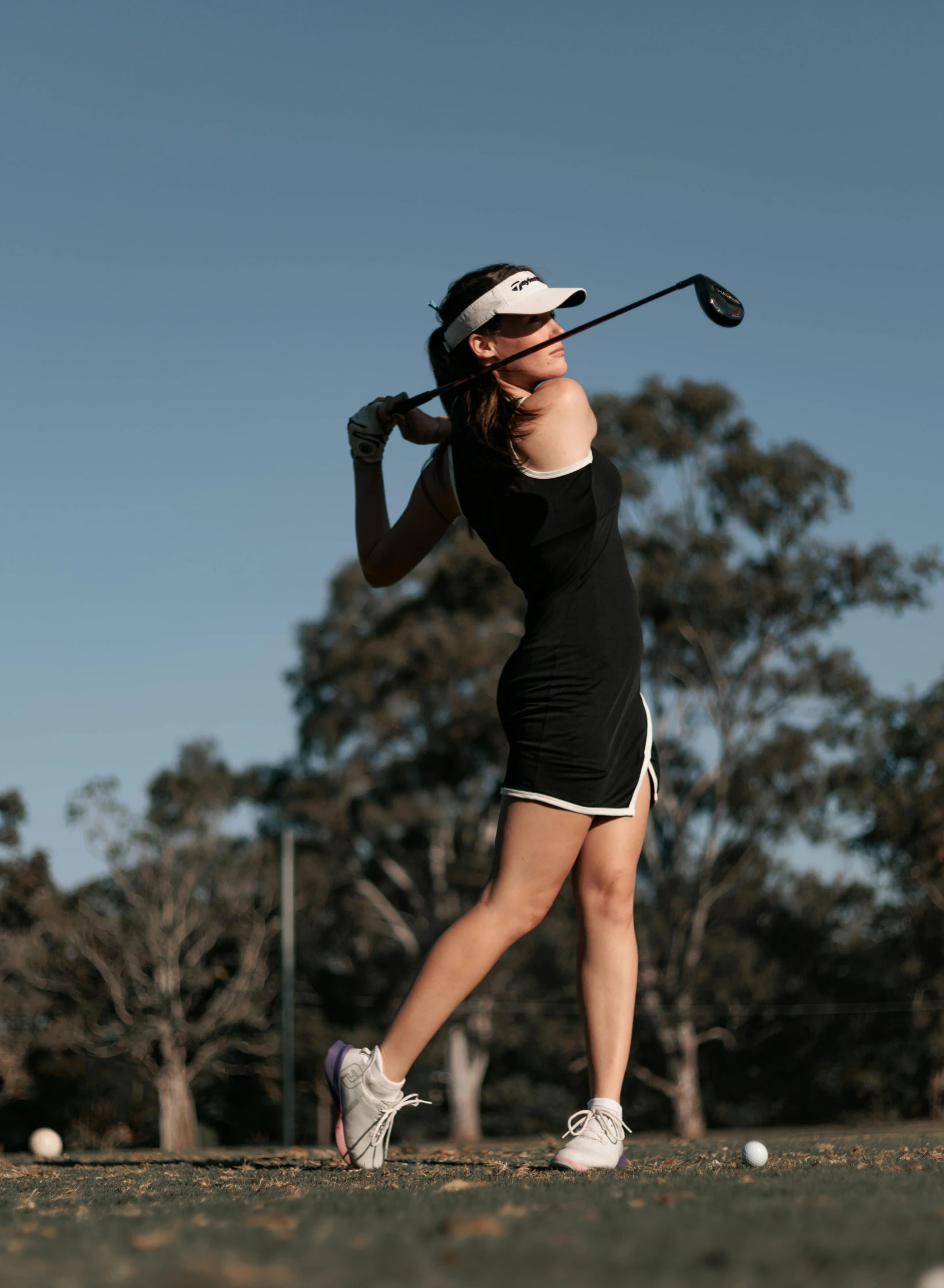 a female golfer is in mid swing at the ball