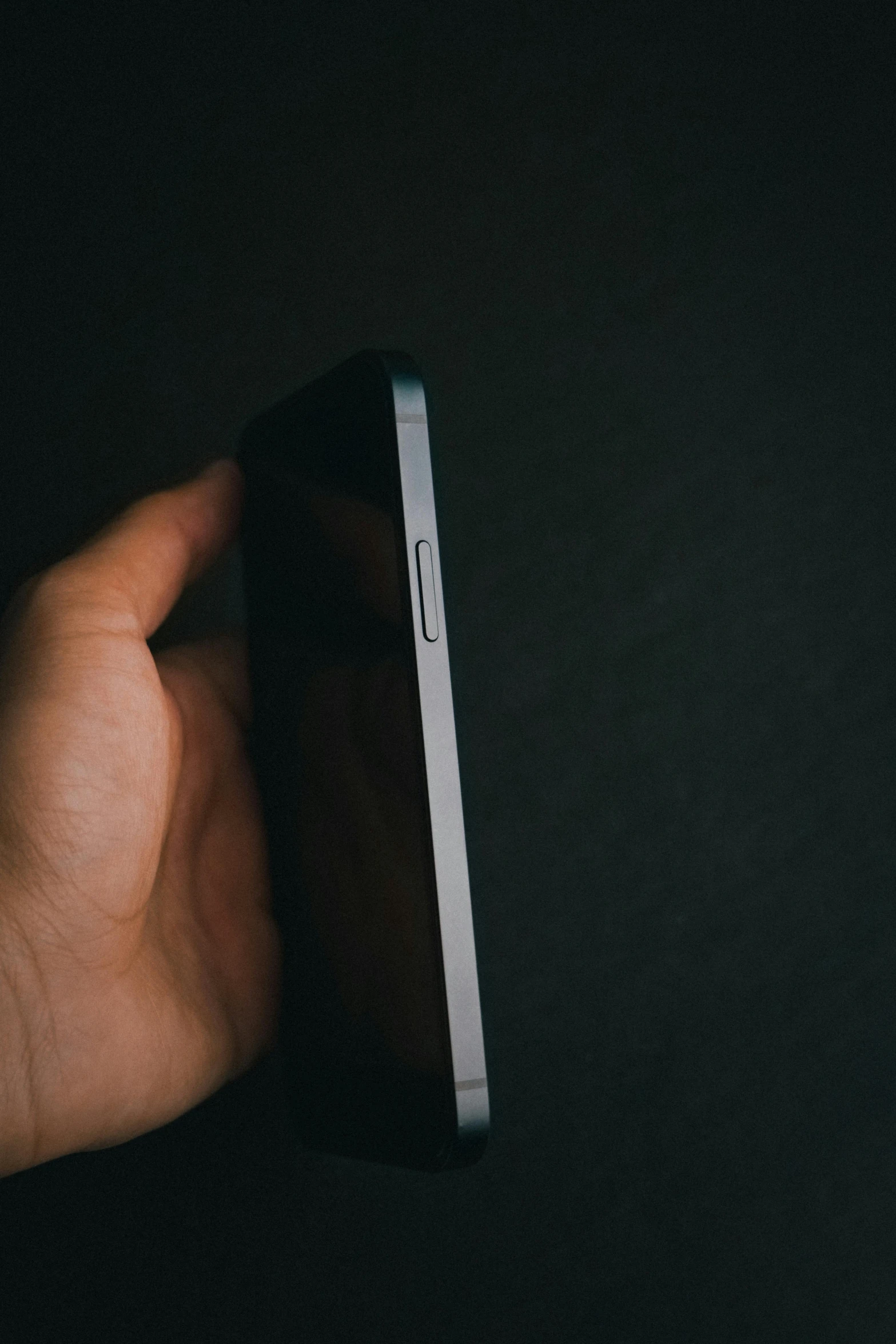 a hand holding a smart phone that is silver