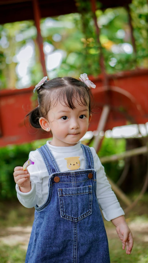 a toddler in overalls holding a tooth brush