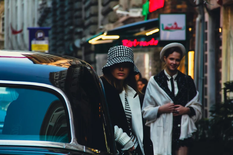 a man and woman walk past a car