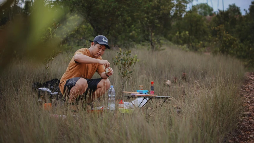 a person sitting on the ground in a field with drinks and bottles