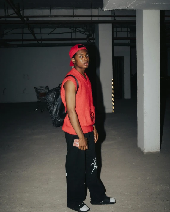 an african american man in red sweater and black pants wearing a backpack