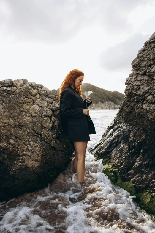 a woman walking in some water and rocks