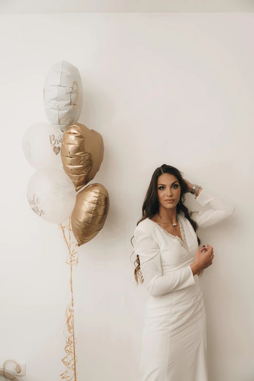 a woman in white is posing near balloons