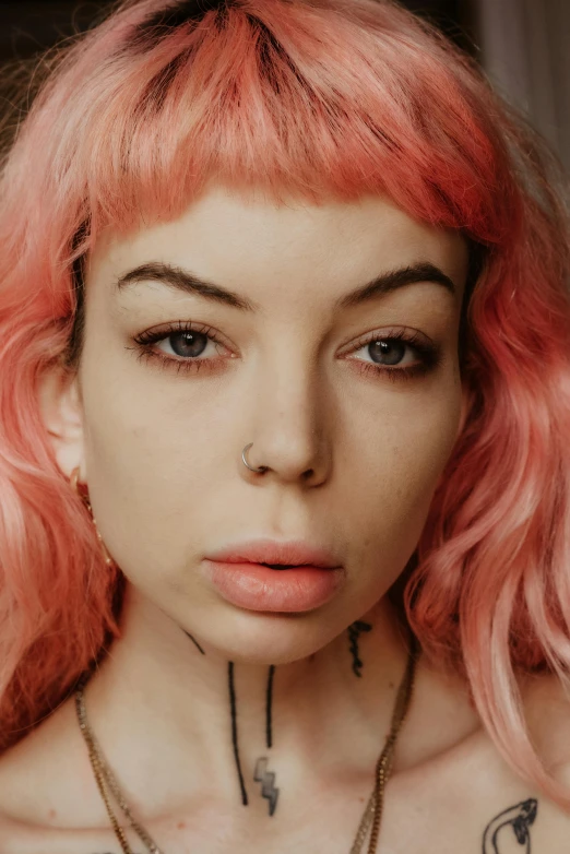 girl with bright pink hair and piercings looks at the camera