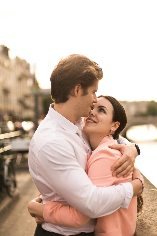 a woman hugging a man on the side of a water way