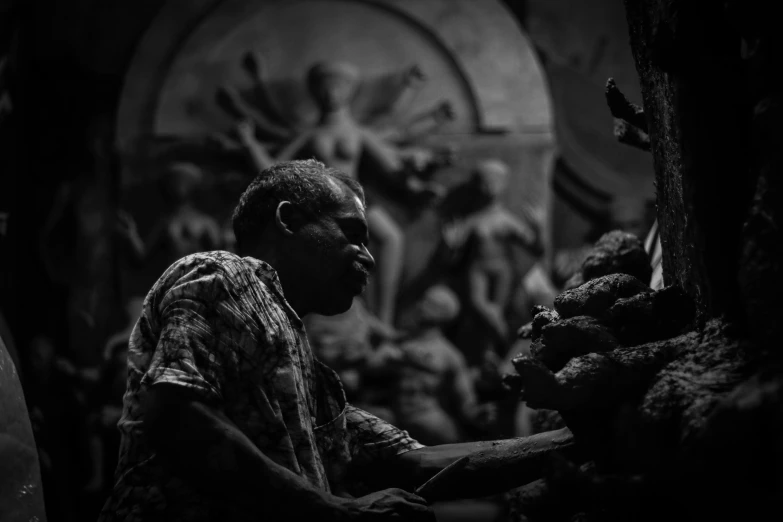 a black and white image of a man standing in front of an elaborate carving