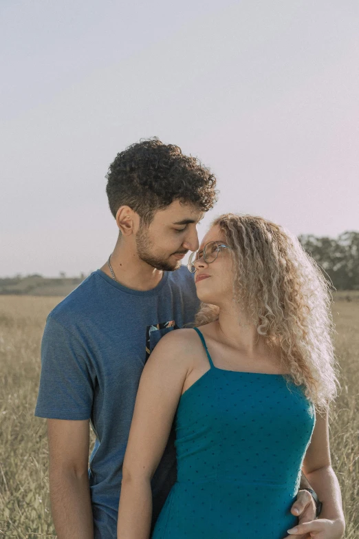 a man and woman stand together in tall grass