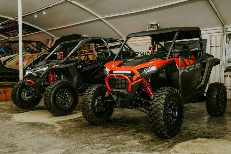 two polaris atvs in a garage are parked with the roof tent folded