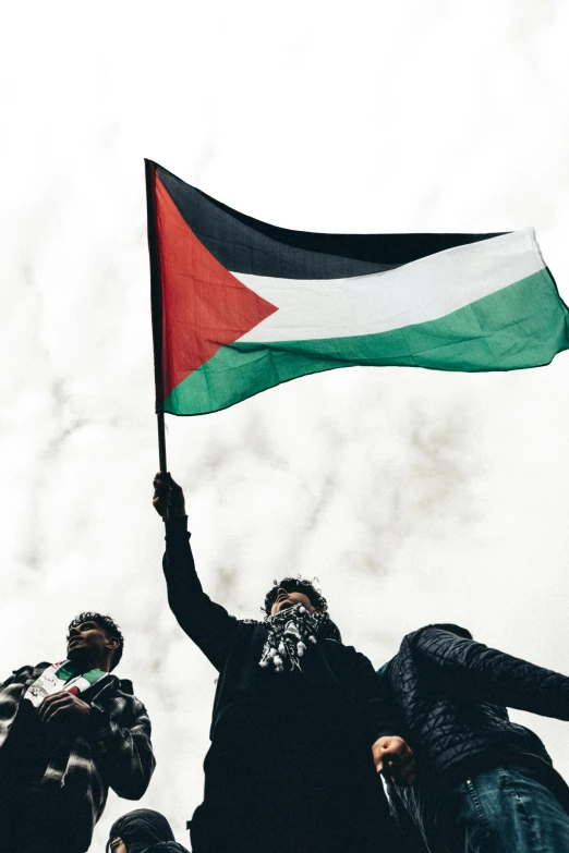 people holding up a flag in the sky