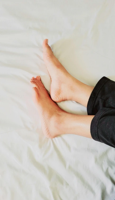 two bare feet on a white sheet with black cloth