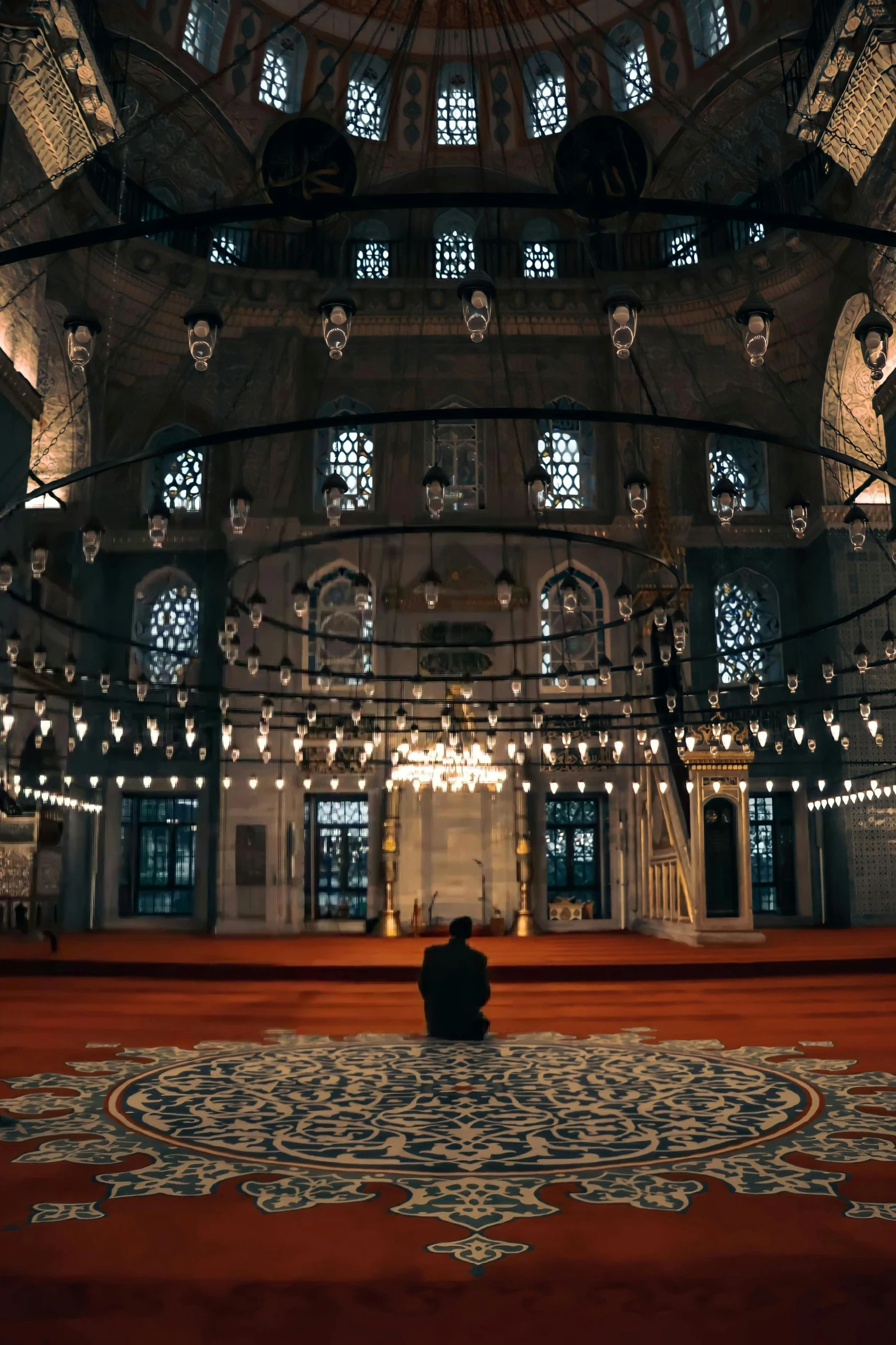 a man is sitting alone in a large, elaborate room with white and blue chandeliers hanging from the ceiling