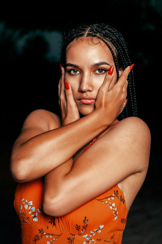 a woman is wearing a short orange dress and has her hands over her face