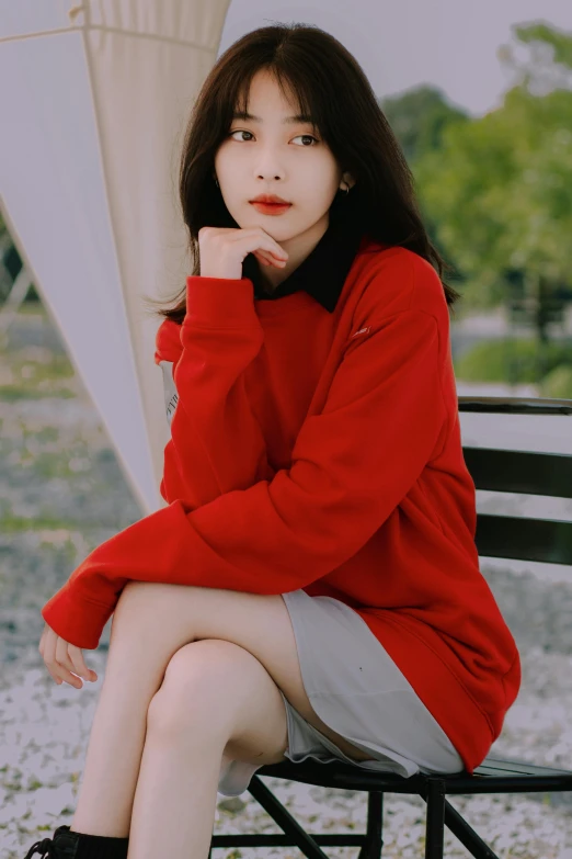 a woman sitting on a bench, wearing a red top