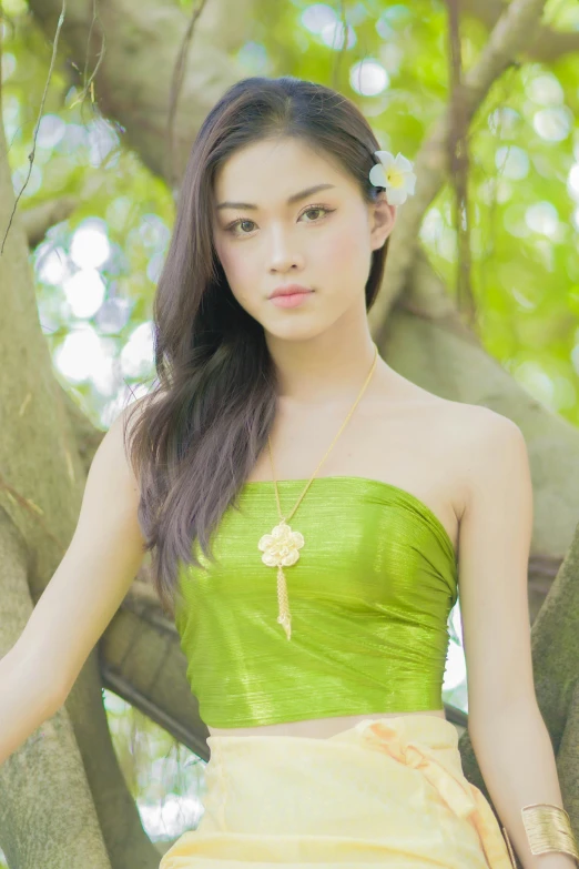 a young lady standing under a tree wearing a green dress