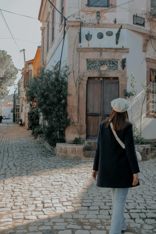 woman walking along street in front of old house