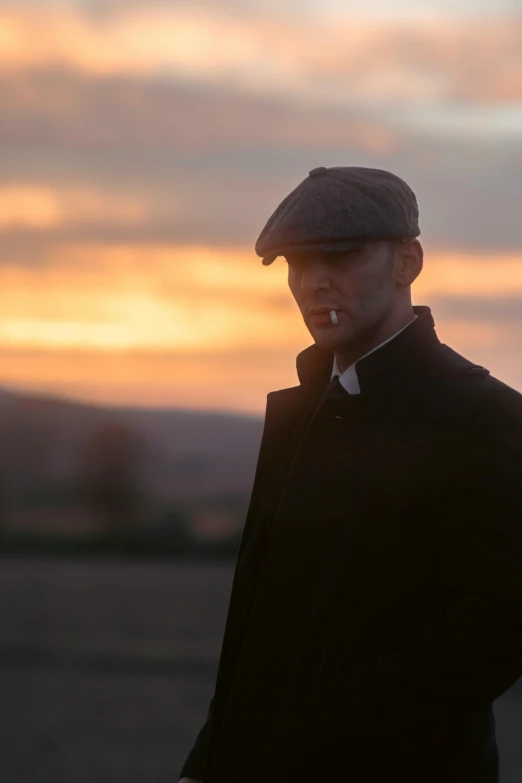 a man with his cap on is smoking in the sunset