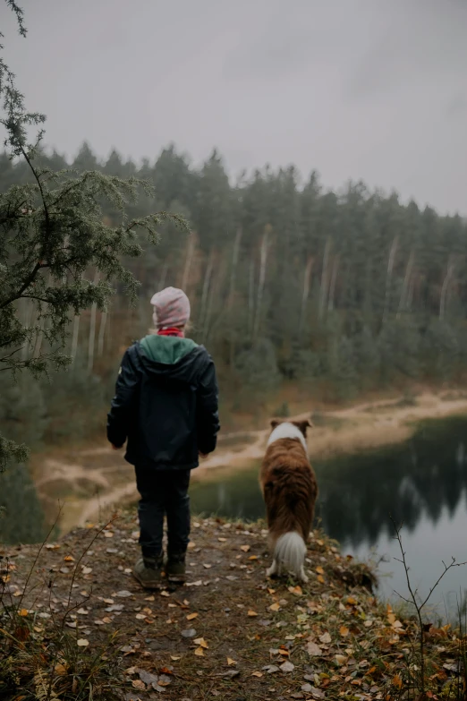 a person standing on a trail next to a dog