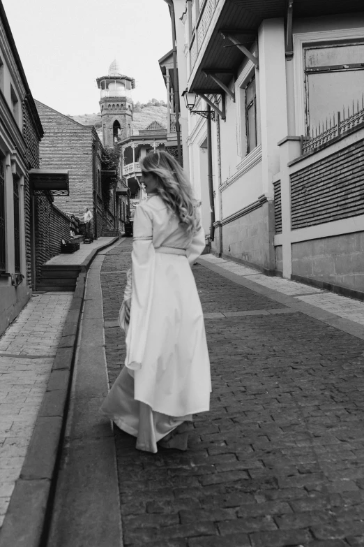 a woman walking down the street in a white dress