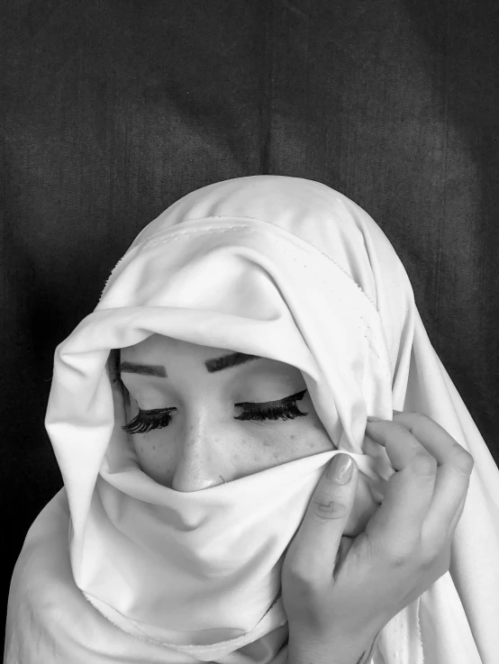 a woman with black eyes hiding her face under a blanket