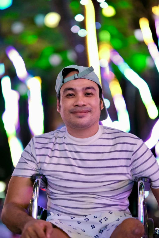 a man in a wheel chair smiles with lights in the background