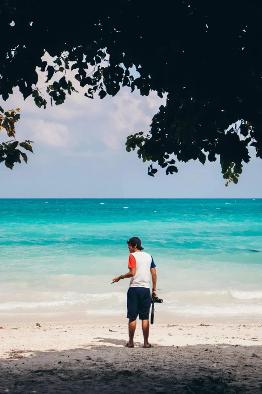 a man is standing by the ocean with a camera