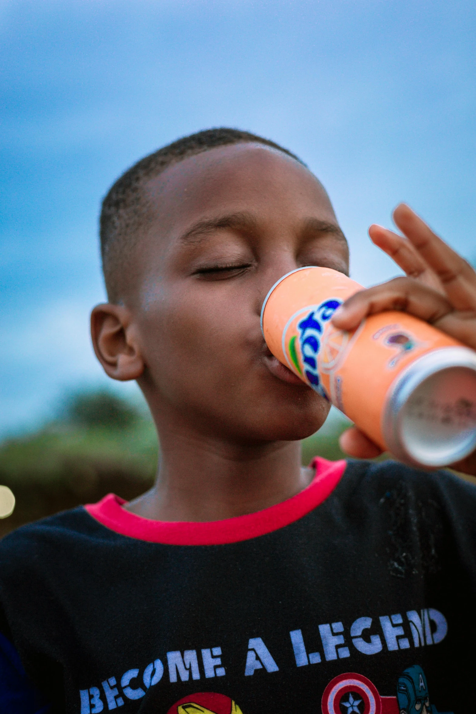 a  drinks from an orange can