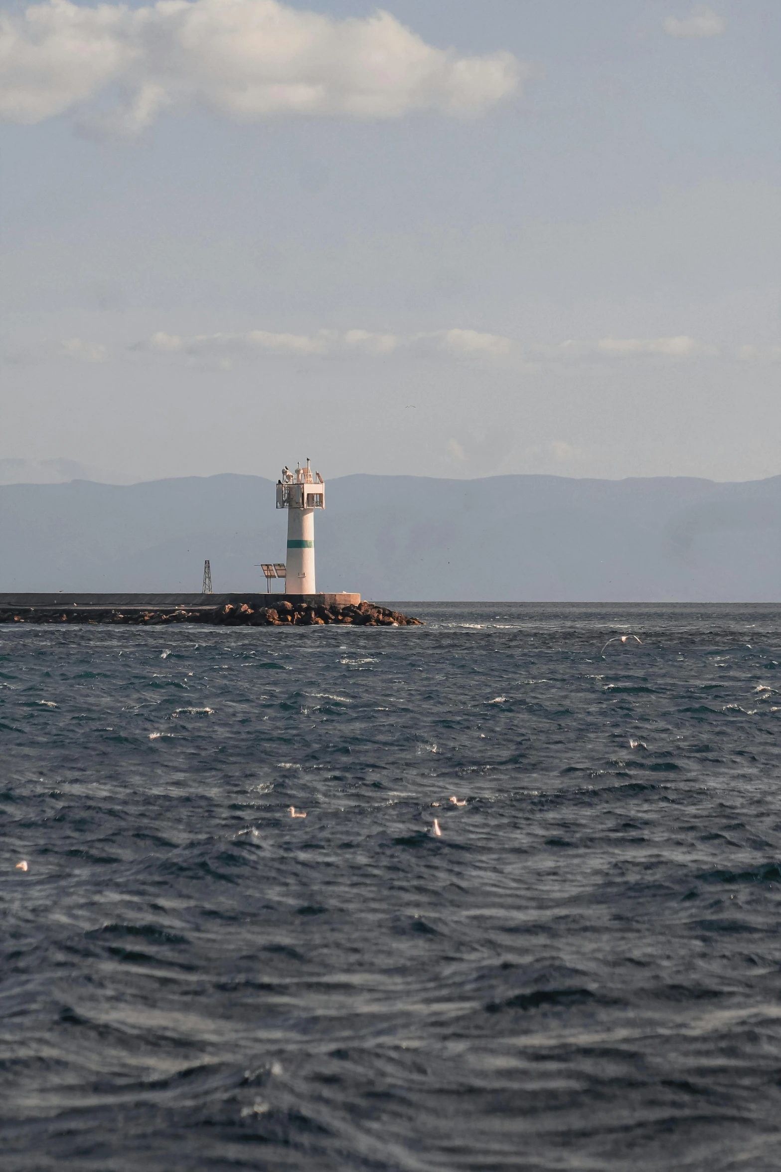 a small light house in the middle of the ocean