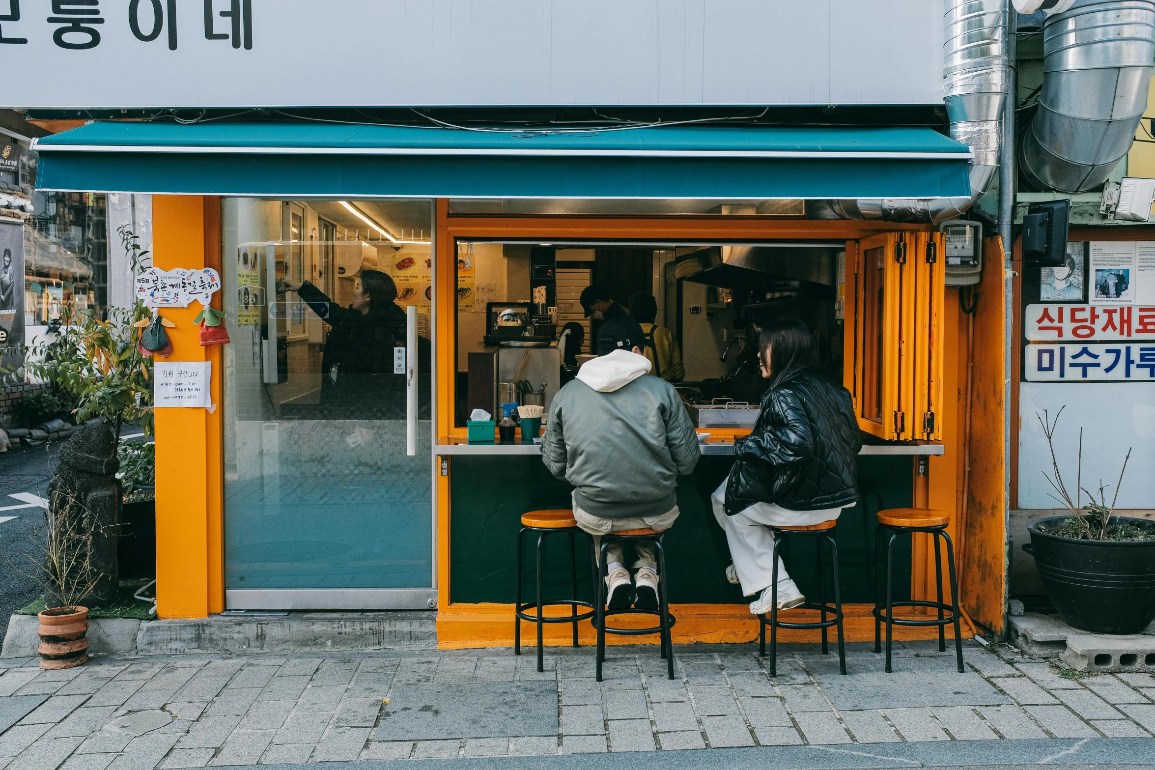 two people sit at small tables outside a store