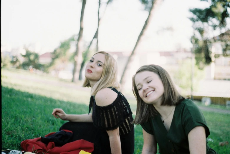 two young women sitting on the grass together