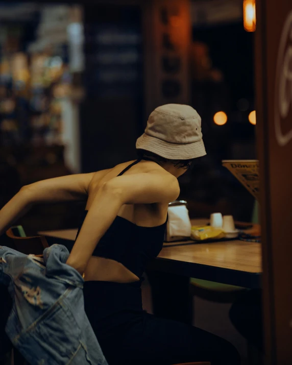 woman with hat sitting at table with beer in glass