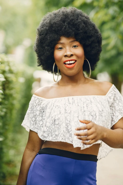 woman with afro and curly hair smiling in park