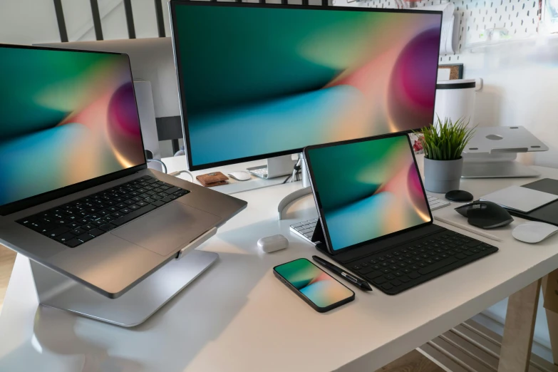 three different laptops and a cellphone on a desk