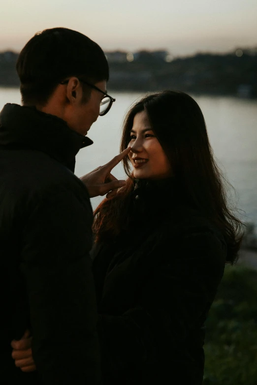 a couple standing near the water touching hands