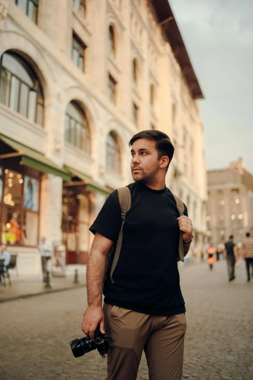 a man walking down a street with camera equipment in his hand