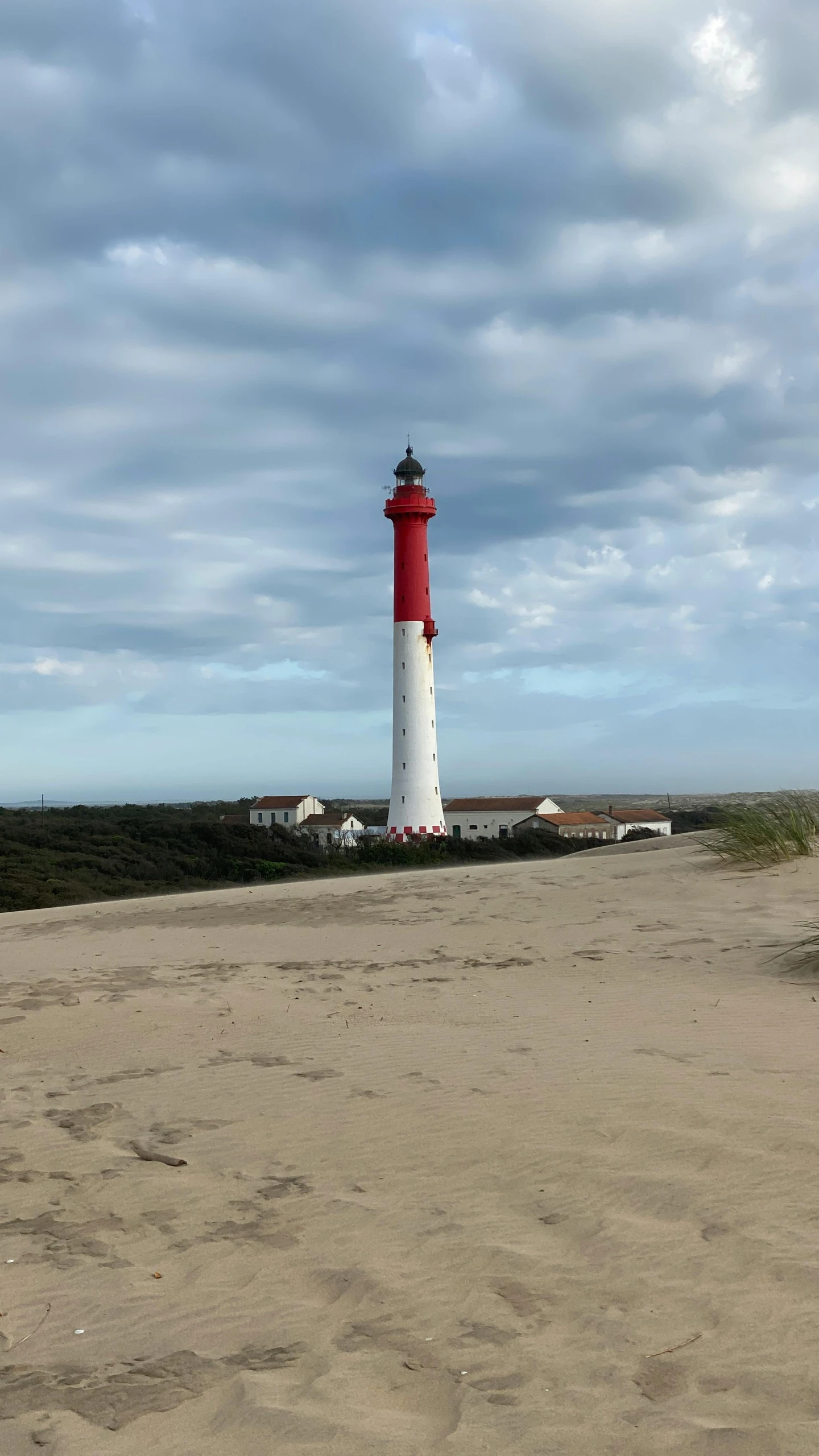 a lighthouse is surrounded by clouds near a beach