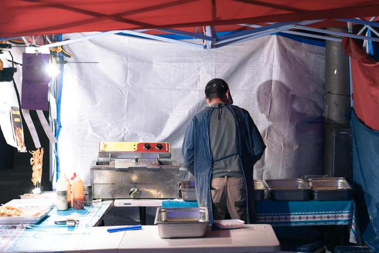 a man wearing a hat and walking around a table in front of food