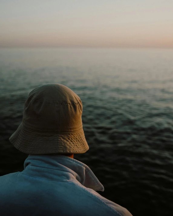 a man who is sitting down on the edge of the ocean