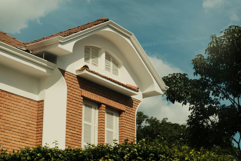 a red brick house with white shutters on a blue sky day