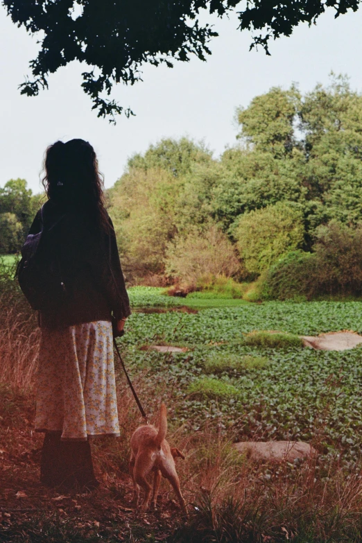 there is a woman walking a dog in the grass