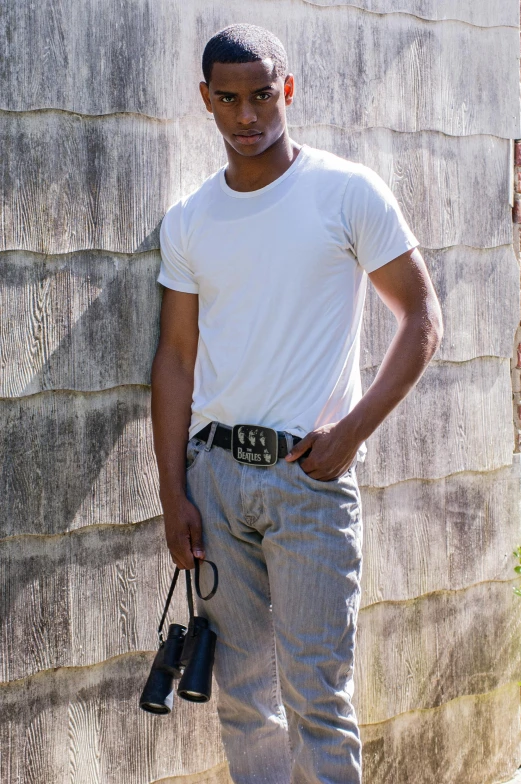 man standing with camera and carrying bag near a house