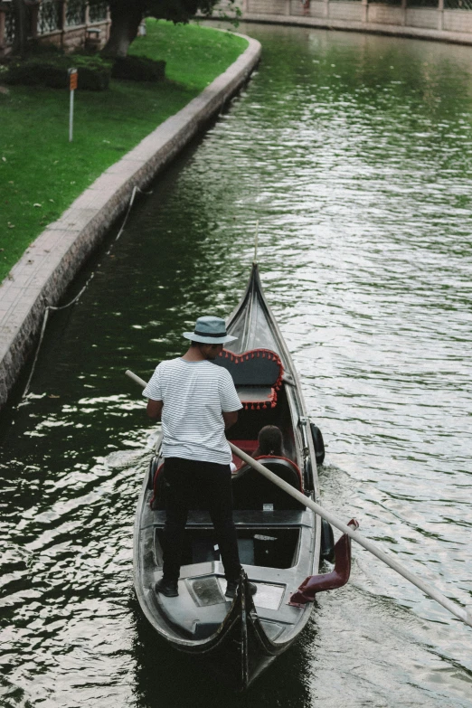 two people rowing a boat on a small body of water