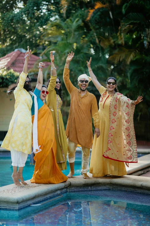 group of people wearing matching clothes standing next to pool