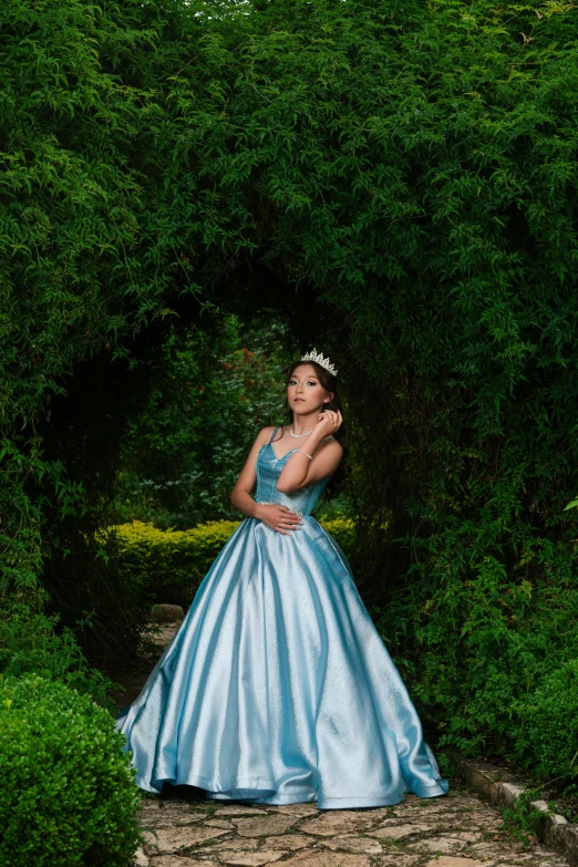 a  in blue gown stands near trees