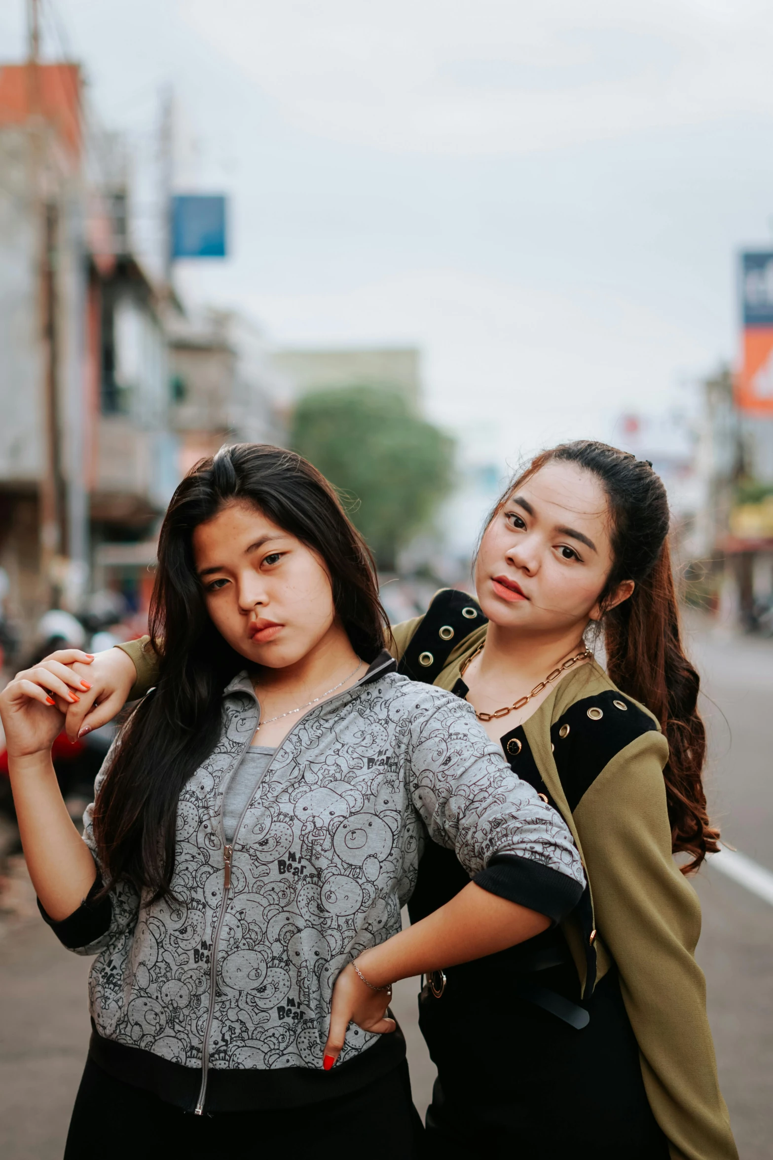 two young women pose with one another on the street