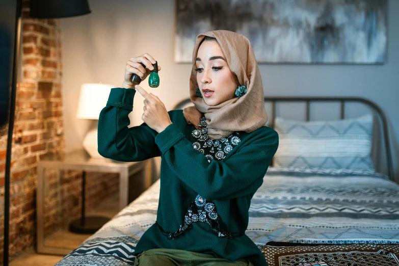 a woman wearing a hijab and holding up her cell phone