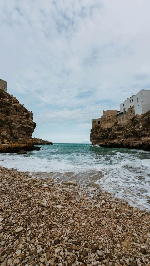 rocky shoreline with buildings on each side and large blue water